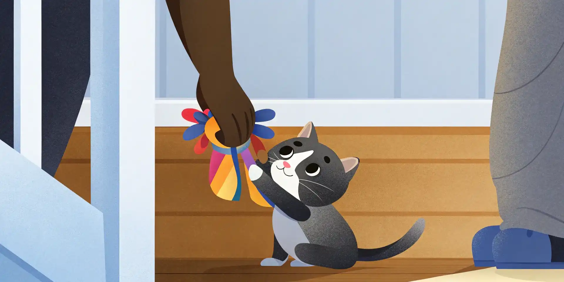 A person holds a colorful plush toy out to a playful kitten